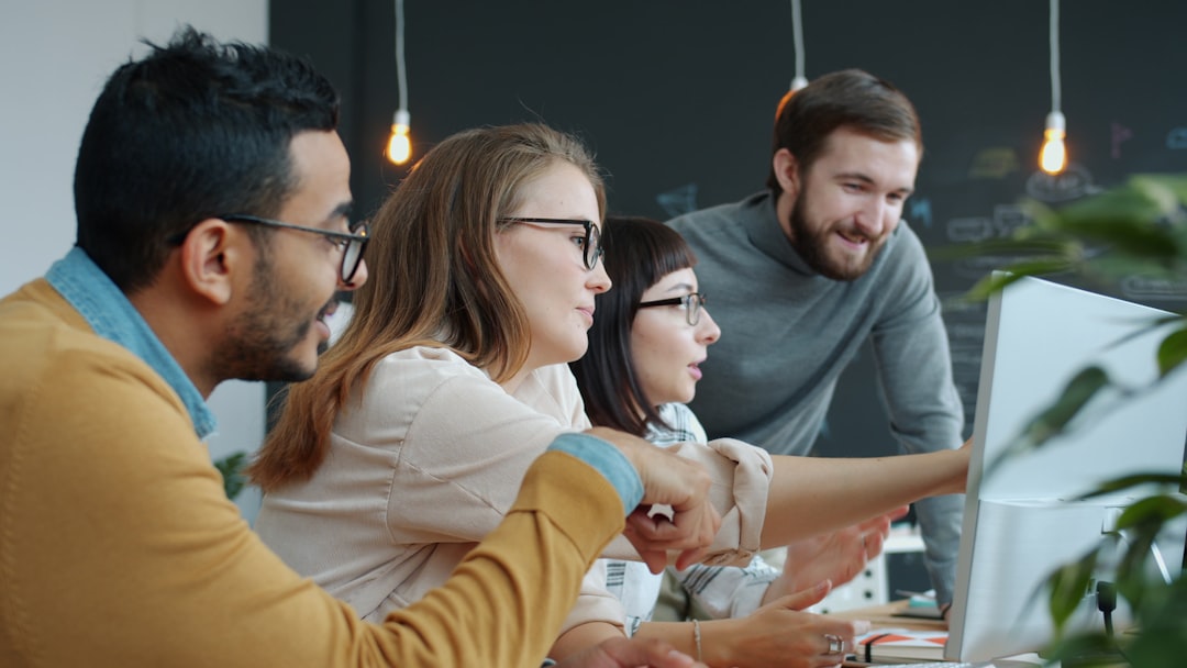 Team discussing work at a computer screen, reflecting the collaboration goals of an employee-first digital workplace