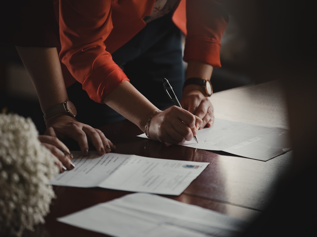 Twee mensen die documenten ondertekenen aan een bureau, het moment waarop eisen voor cyberverzekeringen contractueel worden